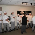 A group of chefs standing in front of a wall.
