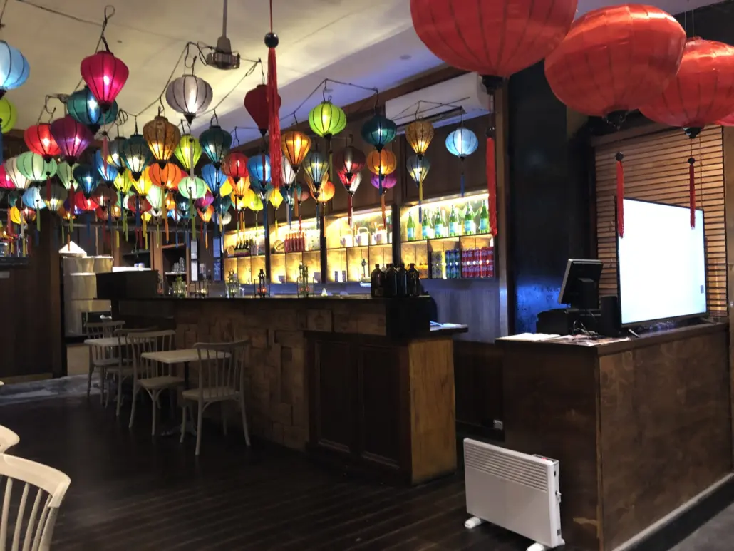 A bar with many colorful lights hanging above it.