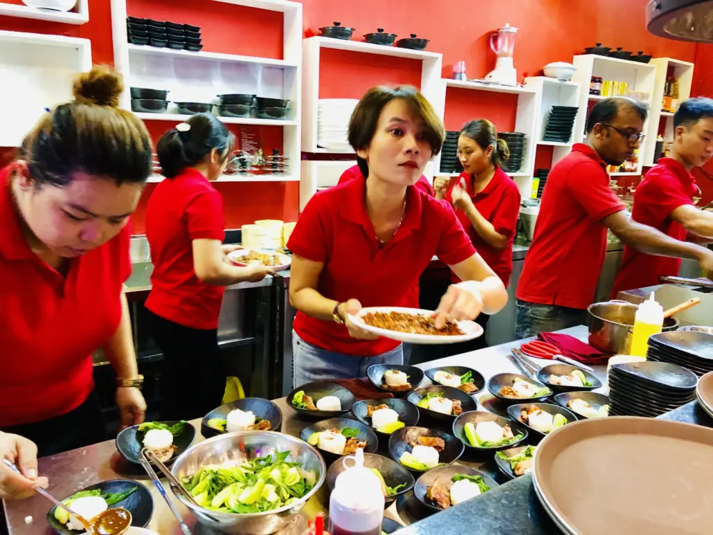 A group of people in red shirts preparing food.