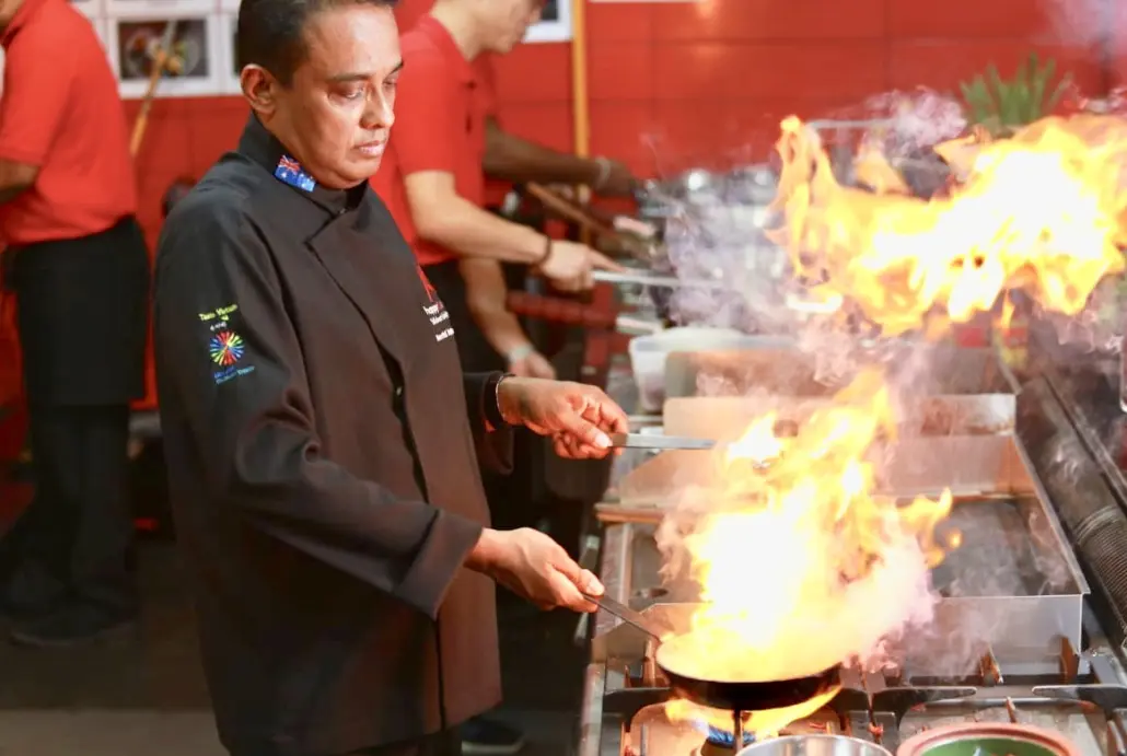 A man in black jacket cooking on fire.
