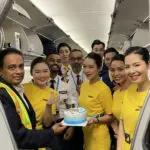 A group of people on an airplane holding a cake.