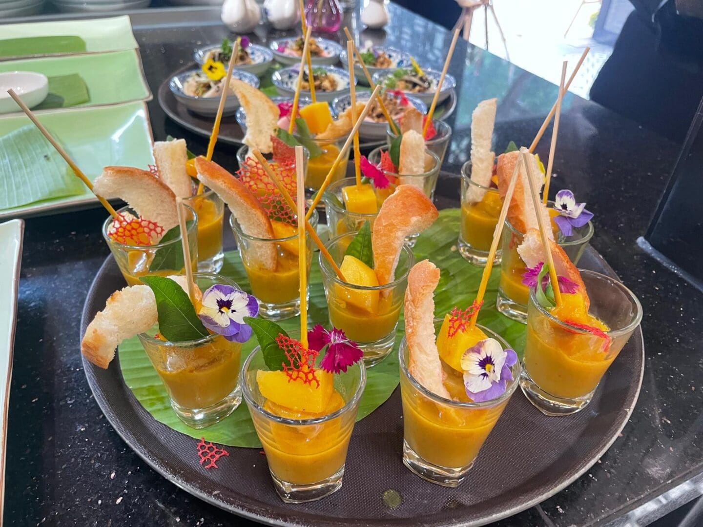 Yellow soup shooters with bread and flowers.
